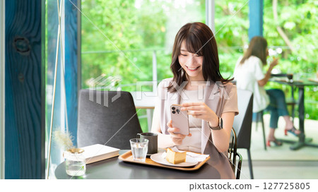 一位女士在咖啡館拍攝蛋糕 一位女士在咖啡館拍攝蛋糕 127725805