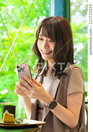Smiling woman using a smartphone in a cafe 127725813