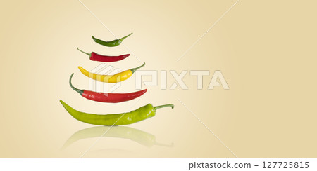 Red, green and yellow hot pepper flying in the air on a beige background. Healthy food, fresh healthy vegetables from the garden Red, green and yellow hot pepper flying in the air on a beige background. Healthy food, fresh healthy vegetables from the garden 127725815