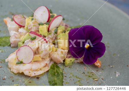 Fresh dorade and shrimp ceviche with avocado, radish, and edible flower on a decorated plate 127726446