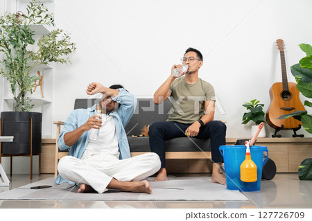 Hydration and Relaxation. Young men drinking water while enjoying a casual moment at home. Hydration and Relaxation. Young men drinking water while enjoying a casual moment at home. 127726709
