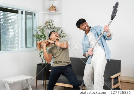 Energetic cleaning session. Friends jamming while vacuuming, creating a fun atmosphere. 127726825