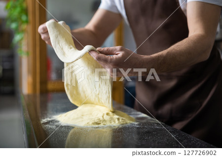 Close up of female hands holding dough for pizza 127726902