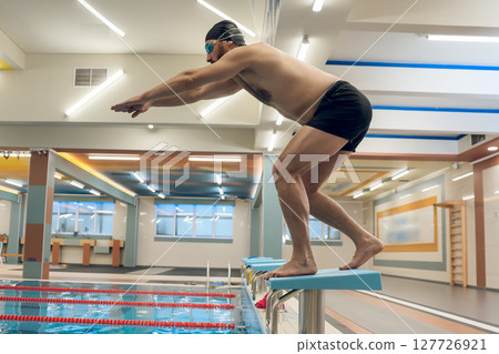 Man having a workout in the swimming pool and getting ready to jump Man having a workout in the swimming pool and getting ready to jump 127726921