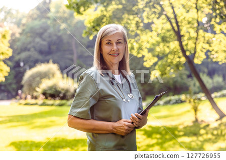 Portrait of medical worker standing in park with green background Portrait of medical worker standing in park with green background 127726955