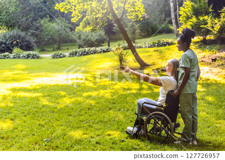 Caregiver assisting senior in rehab session in park landscape Caregiver assisting senior in rehab session in park landscape 127726957