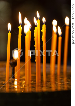 Burning prayer candles illuminating church interior with soft warm light Burning prayer candles illuminating church interior with soft warm light 127727277