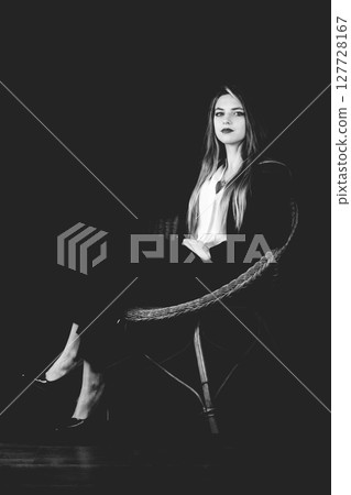 Portrait of beautiful woman with dark suit sitting in wicker chair Portrait of beautiful woman with dark suit sitting in wicker chair 127728167