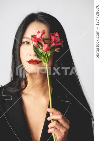 Asian woman portrait cover her one eye with flower 127728676