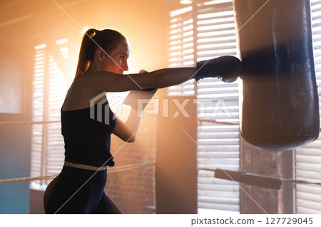 Women self defense girl power. Strong woman fighter training punches on boxing ring. Healthy strong girl punching boxing bag. Training day in boxing gym. Strength fit body workout training 127729045