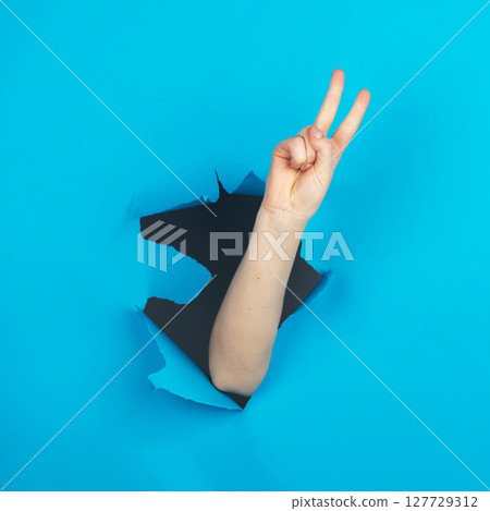 Hand and holding v finger combination in blue background 127729312