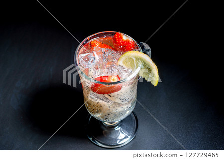 A glass with a refreshing cocktail of sliced pitahaya and strawberries with ice. A glass with a refreshing cocktail of sliced pitahaya and strawberries with ice. 127729465