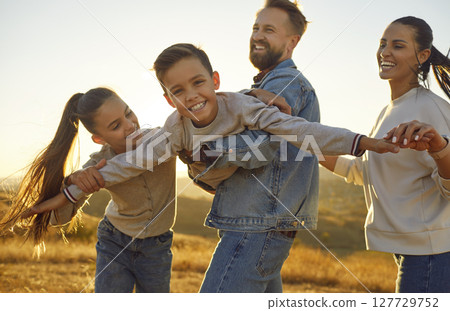 Happy young family of four with two kids having fun in the field at sunset. 127729752