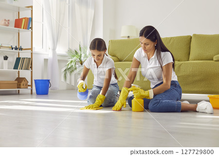 Smiling mother with daughter washing the floor in the living room at home. 127729800