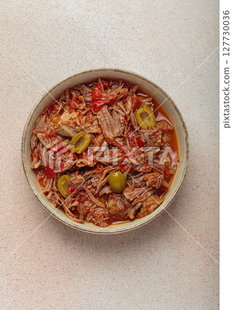 Ropa vieja with white rice, tomato sauce and green olives on a plate top view, traditional dish of Cuba 127730036