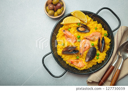 Spanish seafood Paella with shrimps, mussels, peas and lemon in a pan on grey rustic background top view, space for text Spanish seafood Paella with shrimps, mussels, peas and lemon in a pan on grey rustic background top view, space for text 127730039