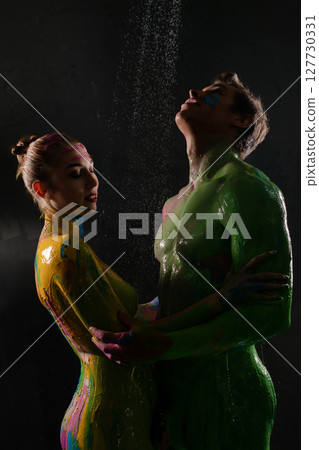 Colorful body paint display with models in artistic pose under rain Colorful body paint display with models in artistic pose under rain 127730331