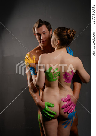 Artistic couple embraces each other with colorful body paint in studio setting 127730332