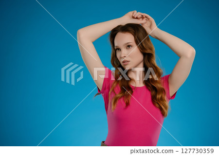 Woman posing in a studio with a bright blue background expressing a range of emotions Woman posing in a studio with a bright blue background expressing a range of emotions 127730359