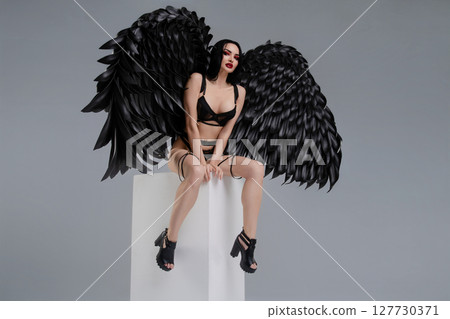 Woman in lingerie with striking black wings posing confidently Woman in lingerie with striking black wings posing confidently 127730371