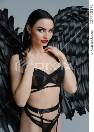 Sensual woman in black lingerie and feathers posing with elegant wings 127730372