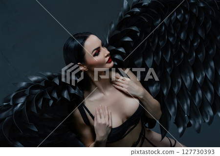 Enchanting beauty in black lingerie with striking wings posing gracefully 127730393