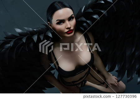 Woman in alluring lingerie with striking black wings poses gracefully Woman in alluring lingerie with striking black wings poses gracefully 127730396
