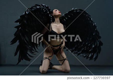 Enchanting woman in lingerie adorned with striking black wings 127730397