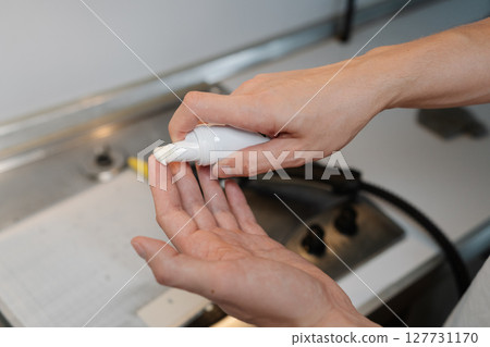 Close-up cropped shot of unrecognizable man pouring cleaning foam from bottle while standing in kitchen near dirty gas stove, preparing to tackle dirt and grime. Concept of cleaning and household. Close-up cropped shot of unrecognizable man pouring cleaning foam from bottle while standing in kitchen near dirty gas stove, preparing to tackle dirt and grime. Concept of cleaning and household. 127731170