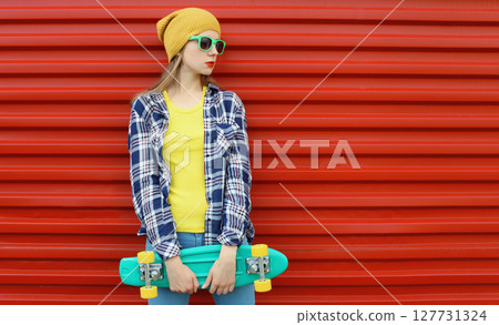Stylish young woman with skateboard, modern teenage girl posing on city street, colorful wall 127731324