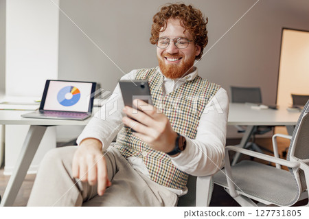 A Cheerful and Engaging Young Professional Enthusiastically Using a Smartphone in a Modern Workspace A Cheerful and Engaging Young Professional Enthusiastically Using a Smartphone in a Modern Workspace 127731805