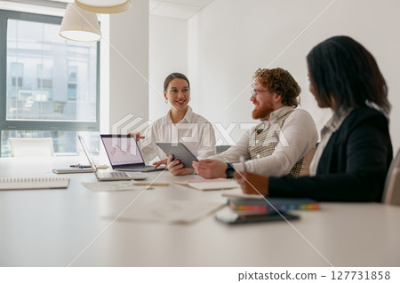 A team meeting occurs in a modern office with devices that enhance collaboration and productivity 127731858