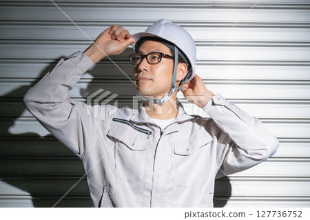 Men in work clothes wearing a helmet Men in work clothes wearing a helmet 127736752