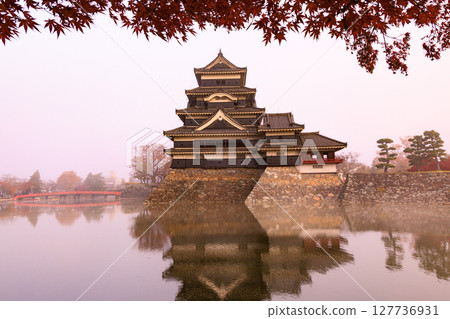 Japanese landscape: Matsumoto Castle with autumn leaves shrouded in morning mist 127736931