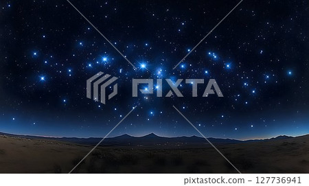 Pleiades Star Cluster Shines Above a Desert Landscape Under a Da 127736941
