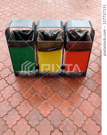 trash bins organized by color for waste segregation in a public area. closeup. trash bins organized by color for waste segregation in a public area. closeup. 127737131