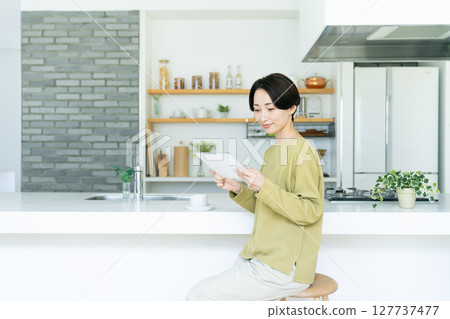 Middle woman using a tablet in the kitchen 127737477
