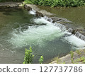 Water flowing through a small weir and white splashes 127737786