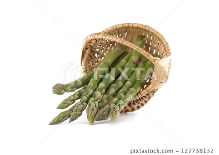 Fresh asparagus spilling from a woven basket on a white background. 127738132