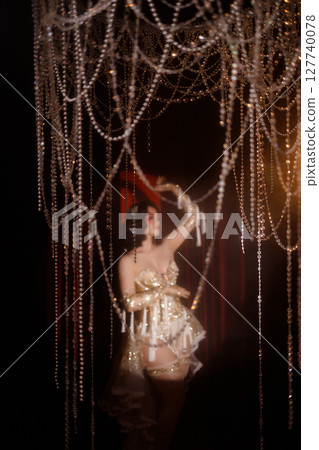 Circus-inspired retro burlesque dancer posing in golden corset with theatrical decor Circus-inspired retro burlesque dancer posing in golden corset with theatrical decor 127740078