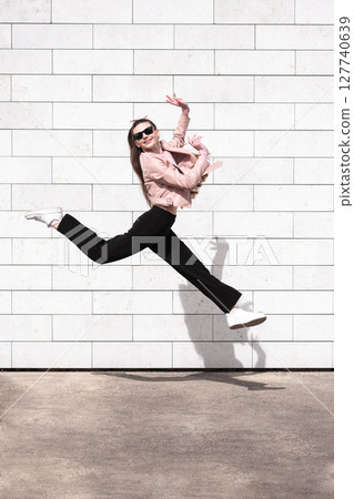 Beautiful woman jumping in brick wall background 127740639