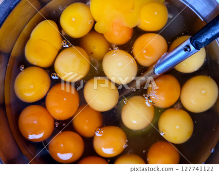 Fresh cracked eggs in a bowl ready for cooking or baking. 127741122