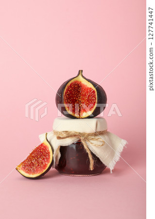 Figs and jar of jam on light pink background 127741447