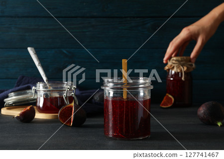 Figs, jars of jam and hand on blue wooden background Figs, jars of jam and hand on blue wooden background 127741467