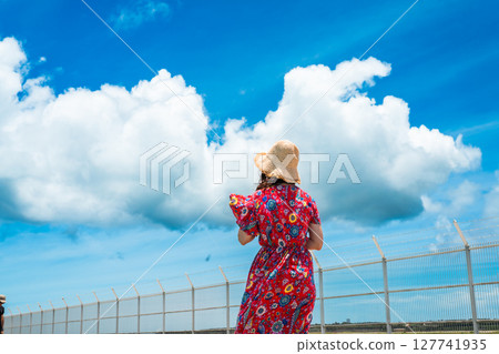A young woman in a dress walking along the water's edge on a tropical beach 127741935