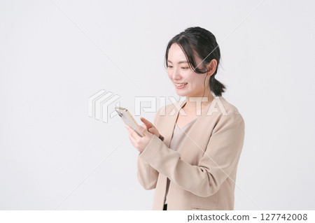 一名二十多歲、穿著西裝、手持智慧型手機的女性 127742008