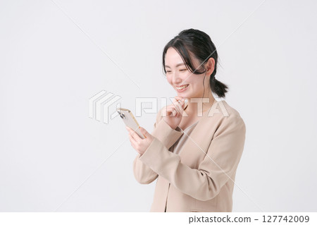 一名二十多歲、穿著西裝、手持智慧型手機的女性 一名二十多歲、穿著西裝、手持智慧型手機的女性 127742009