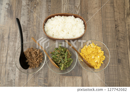 Packing a three-meal rice bowl lunch: minced meat, green beans with sesame dressing, scrambled egg on rice. 127742082