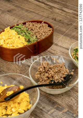 Pack a three-meal rice bowl lunch. Place minced meat, green beans with sesame sauce, and scrambled eggs on rice. Pack a three-meal rice bowl lunch. Place minced meat, green beans with sesame sauce, and scrambled eggs on rice. 127742090