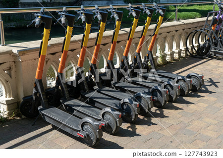 Electric scooters in a row in a parking lot. Electric scooters in a row in a parking lot. 127743923